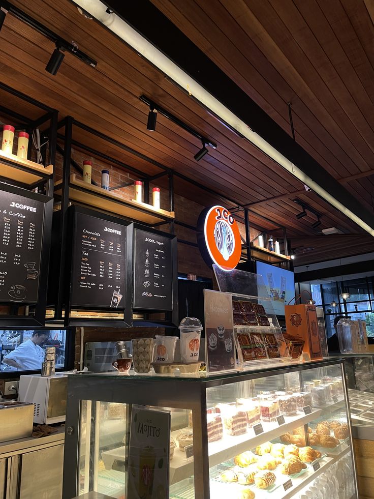 Café interior with glass pastry display case, chalkboard menus, and wooden ceiling