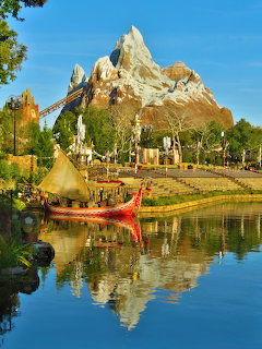 Expedition Everest mountain attraction reflected in calm water with green landscaping and blue sky