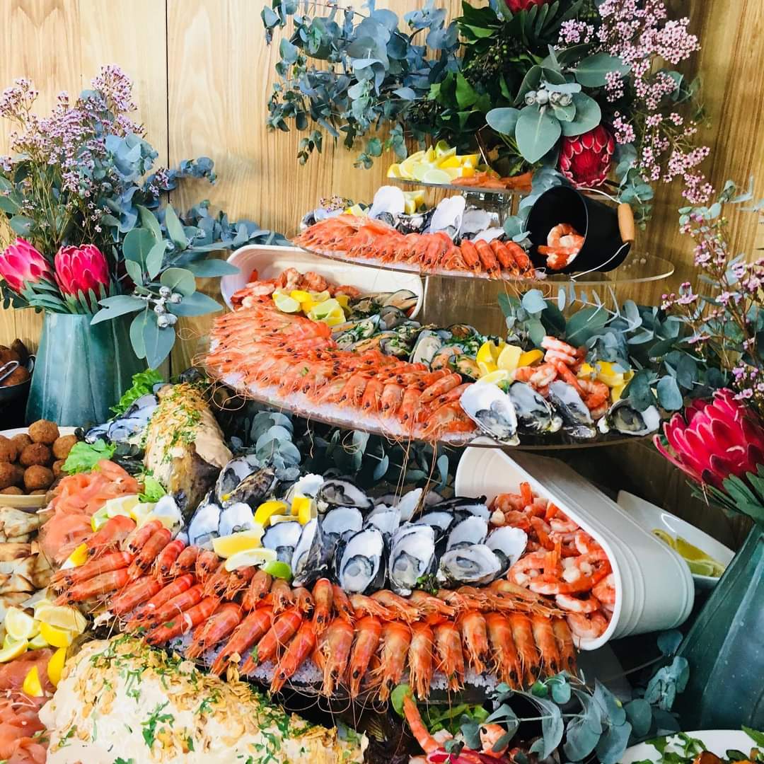 Multi-tiered seafood display with prawns, sushi, oysters and flowers