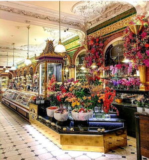 Elegant Harrods Food Hall with ornate ceiling, display cases, and colorful flower arrangements
