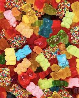 Close-up of colorful gummy bears and round candy pieces covered in rainbow sprinkles