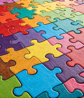 Completed jigsaw puzzle with colorful interlocking pieces in rainbow colors viewed from an angled perspective