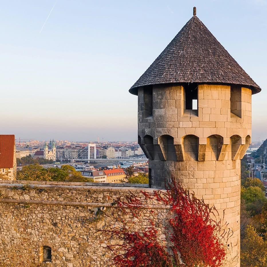 Medieval stone tower with conical roof and city view in background