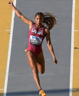 Overhead view of a female long jumper in a USA track uniform landing on a runway