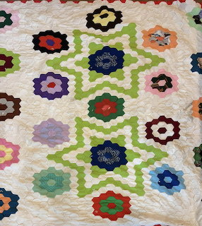 Colorful hexagon flower quilt blocks in diagonal lattice pattern on cream fabric with quilted texture