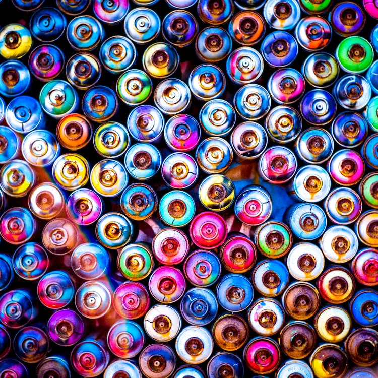 Top view of colorful spray paint can tops arranged closely together