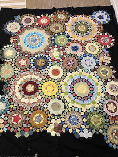 Colorful hexagon patchwork quilt with flower medallions on black fabric background