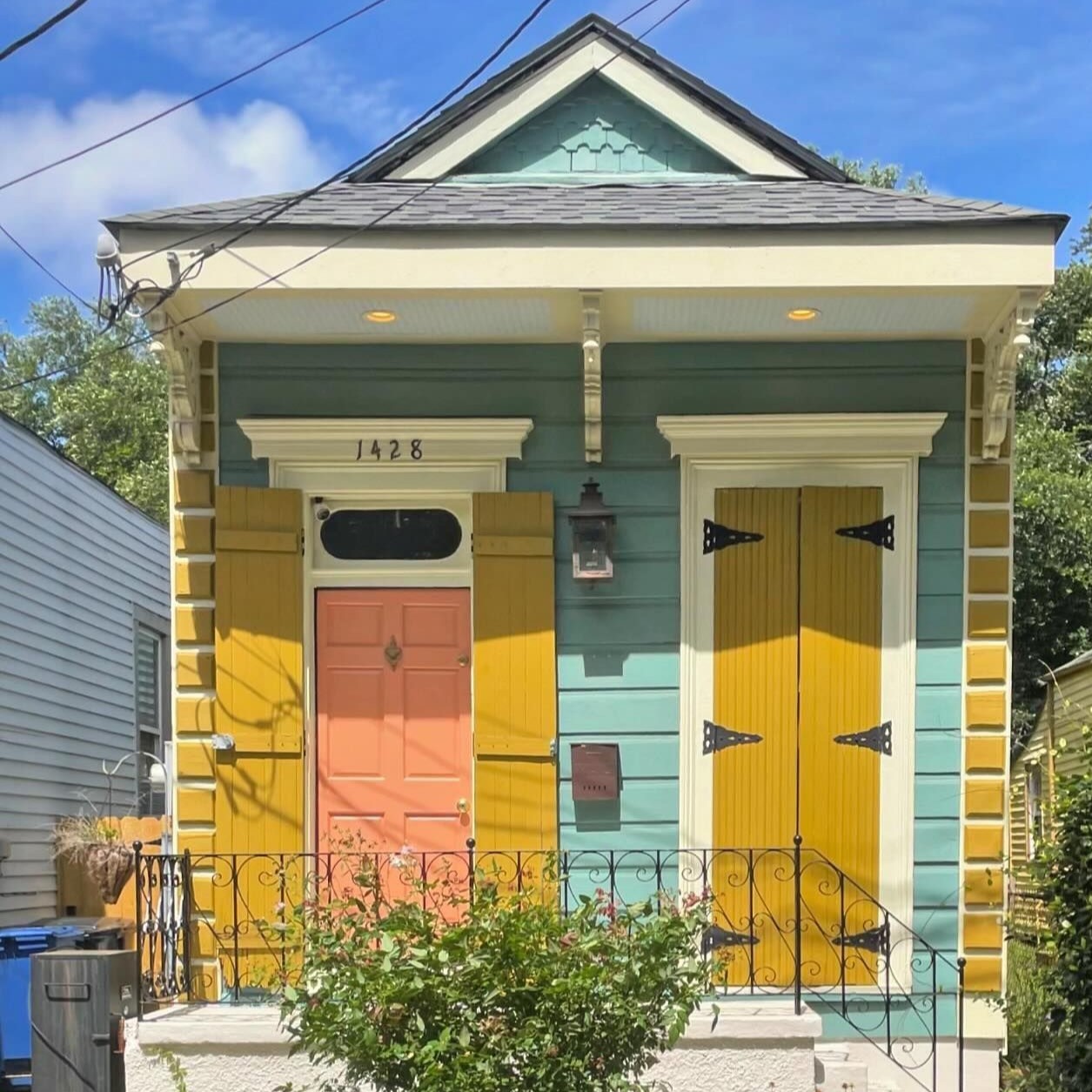 Small house with rainbow-striped siding and yellow doors under blue sky
