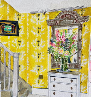 Bright foyer interior with yellow floral wallpaper, white staircase, dresser with mirror and flower arrangement
