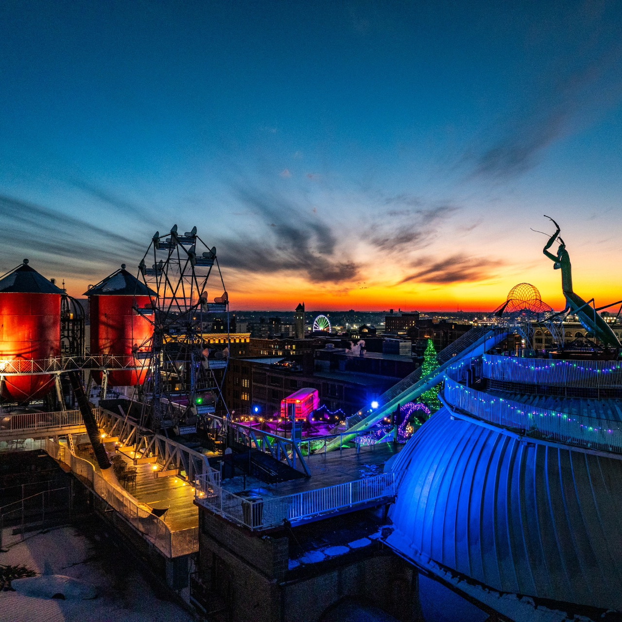 Rooftop of City Museum at sunset with sculptures, blue dome, red silos, and orange sky