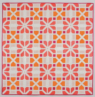 Geometric quilt with coral and pink floral star pattern on cream background