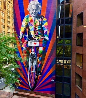 Colorful mural of Albert Einstein riding a bicycle on a city building wall