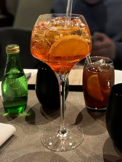 Aperol Spritz cocktail in a wine glass with orange slice on a restaurant table