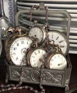 Antique pocket watches in a decorative metal box with pink beaded necklace chains