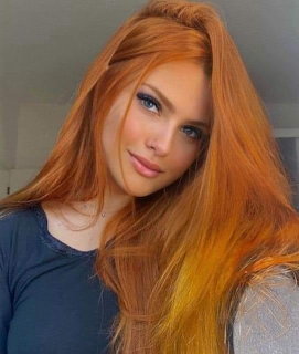Young woman with long red hair and blue eyes wearing a dark navy top