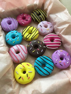 Assortment of brightly colored frosted donuts with decorative chocolate drizzle patterns on white fabric