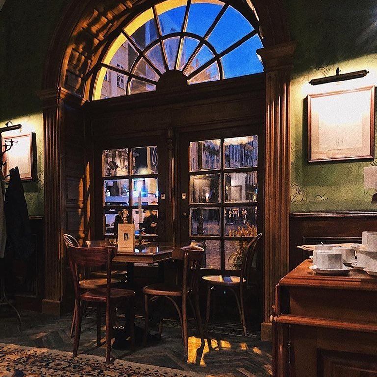 Rustic cafe interior with wooden furniture, arched stained glass window, and warm lighting