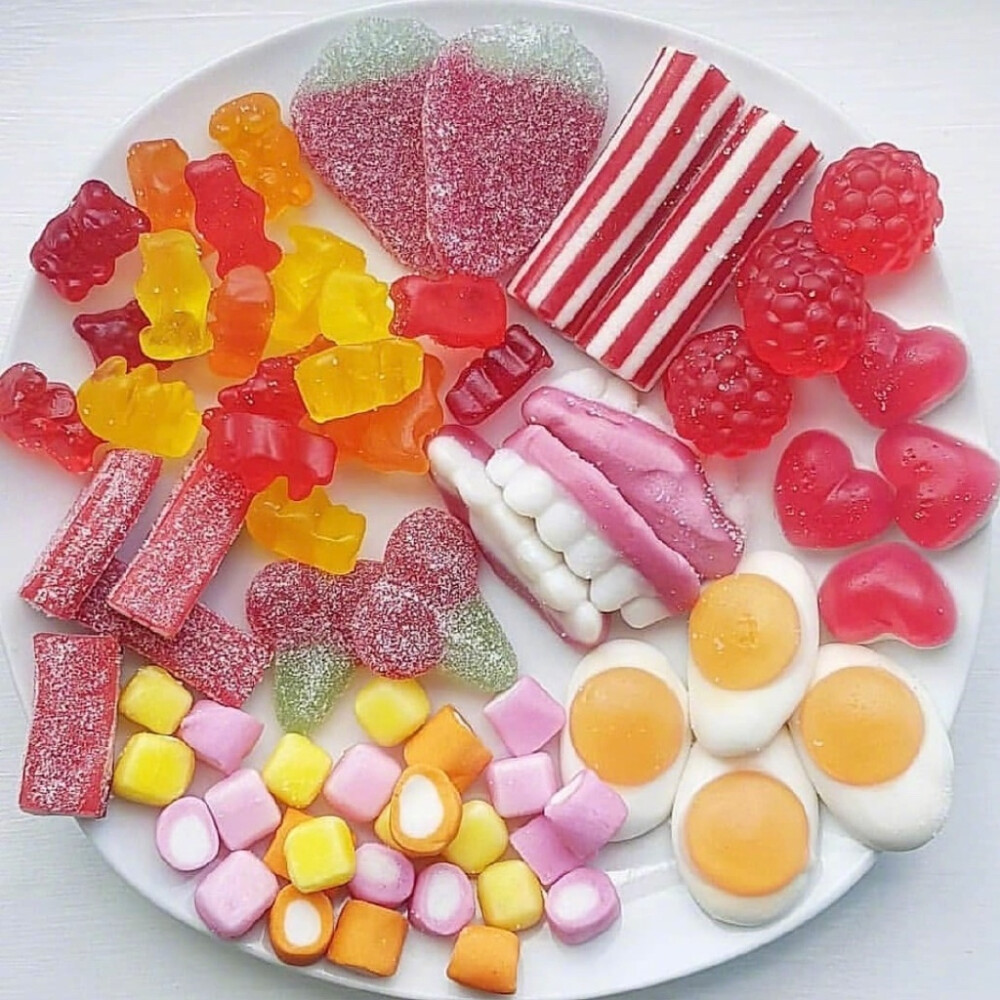 White plate with assorted colorful candies, gummies, marshmallows, and striped sweets