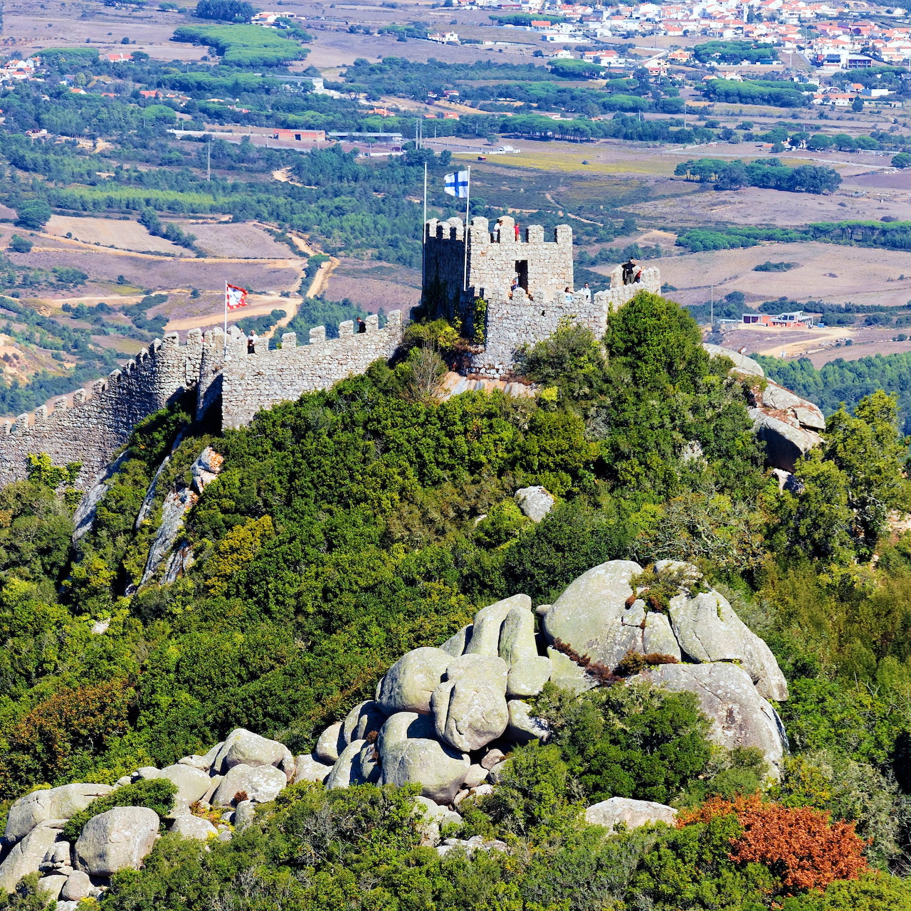 Medieval castle ruins on a forested hill with stone fortifications and countryside views in Sintra, Portugal
