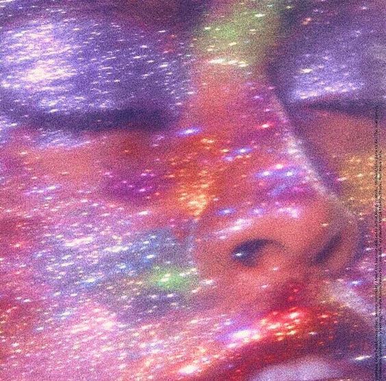 Woman's face covered in colorful rainbow glitter with sparkling light effects