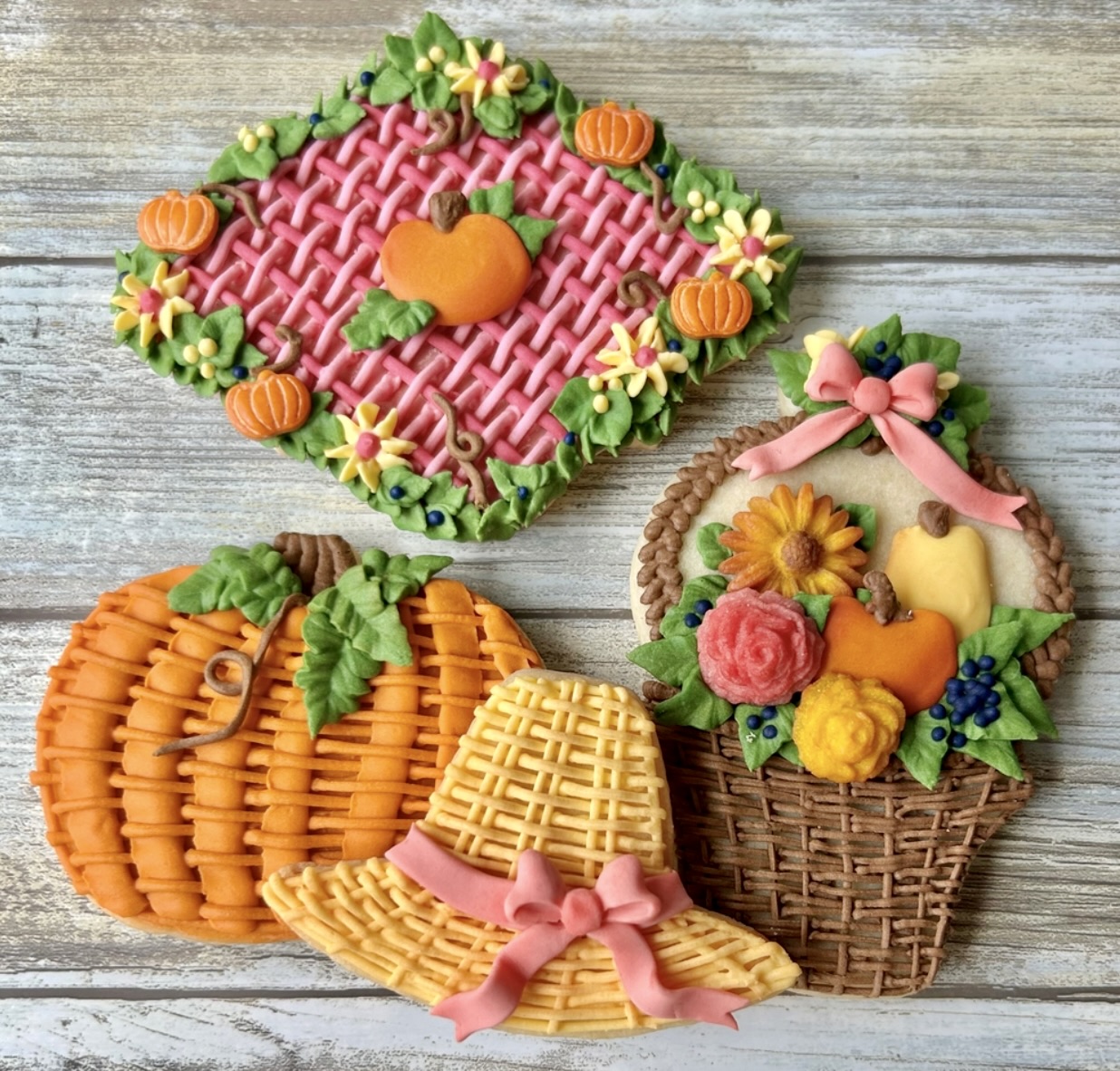 Decorated fall cookies shaped like a kite, pumpkins, hat, and flower basket on wood