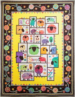 Colorful patchwork quilt with illustrated sheep in various colors and alphabet letters on yellow background