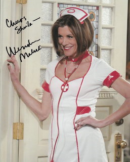 Wendie Malick in a nurse costume holding a signed autographed photo indoors