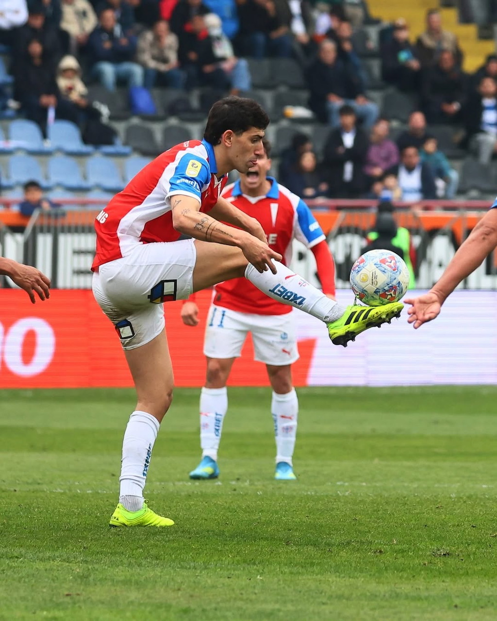 Soccer player Justo Giani kicking a ball during a match on a grass field