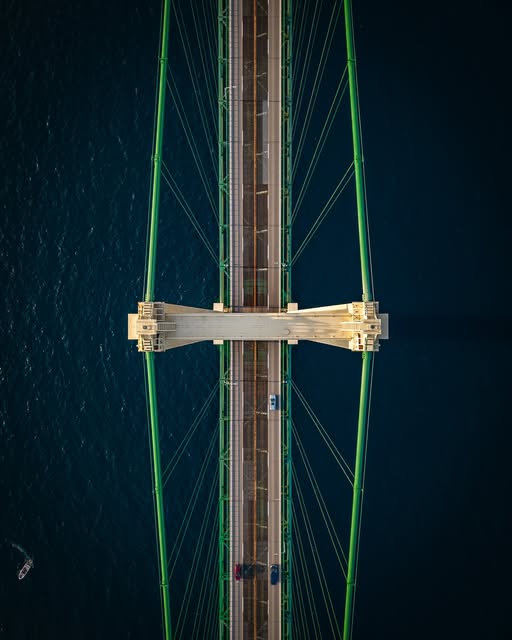 Aerial top view of a suspension bridge over dark blue water