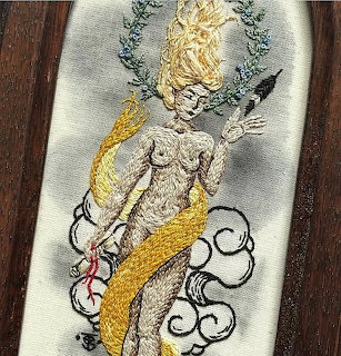 Vintage embroidered mermaid with golden hair and tail on white fabric with decorative border