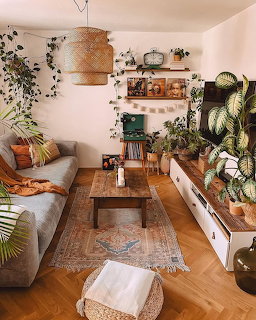 Cozy living room with many houseplants, gray sofa, wooden coffee table, and fireplace mantel
