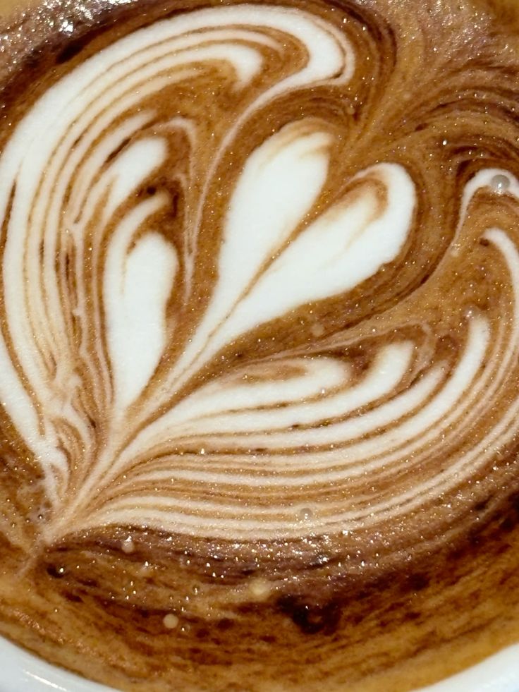 Close-up of latte art showing a heart and leaf pattern in creamy coffee foam