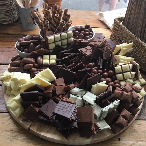 Variety of chocolate pieces and bars arranged on a wooden serving board