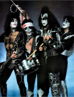 Four members of KISS rock band posing in full face makeup and elaborate studed costumes