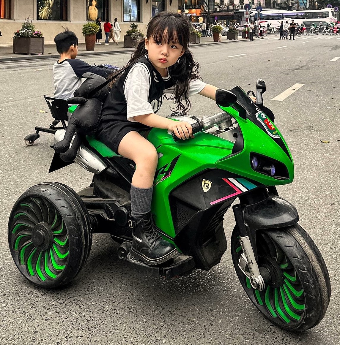 Child sitting on a bright green toy motorcycle outdoors