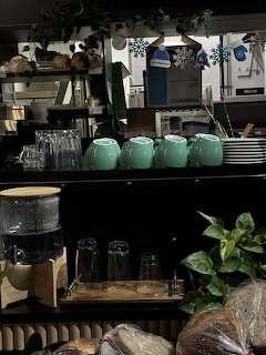 Cafe interior shelves with mint teapots, glasses, plants, and bread