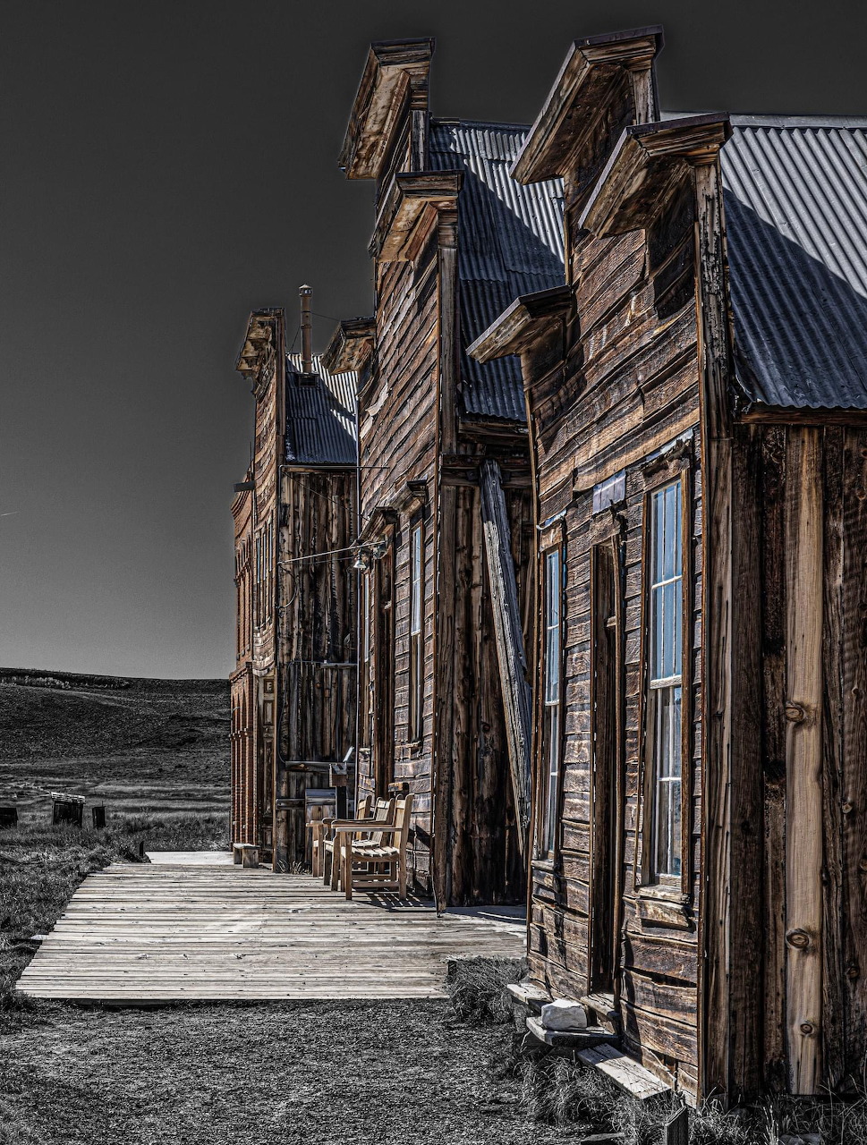 Weathered wooden buildings along a boardwalk in Bodie ghost town, California, with selective color editing