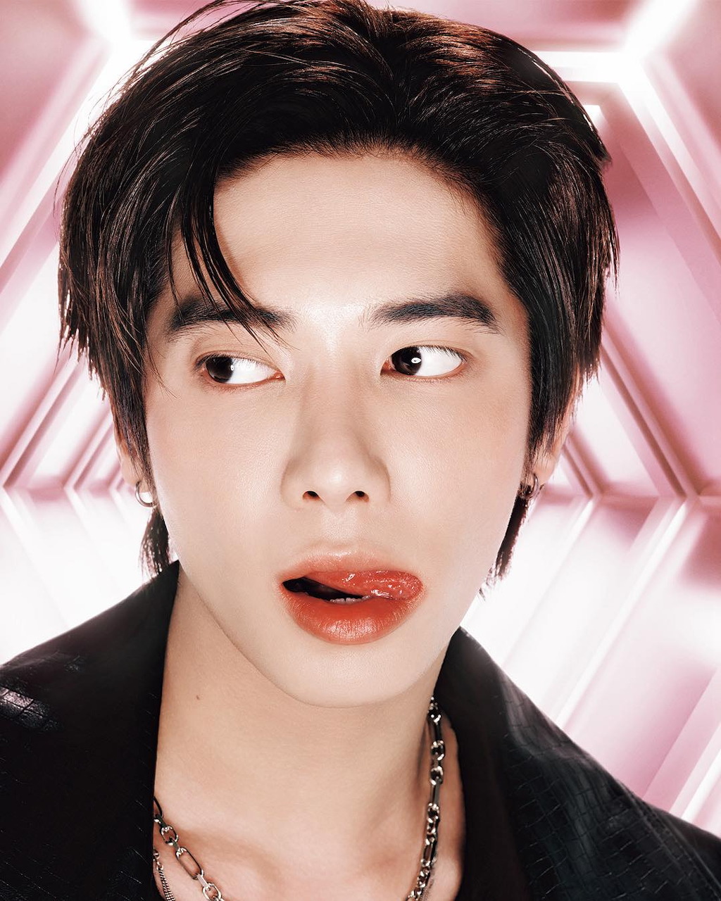 Young male K-pop idol with dark hair, bold red lip makeup, side-eye expression, pink background