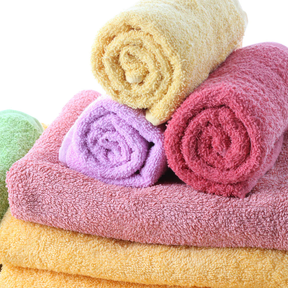 Stack of colorful folded and rolled bath towels on a white background