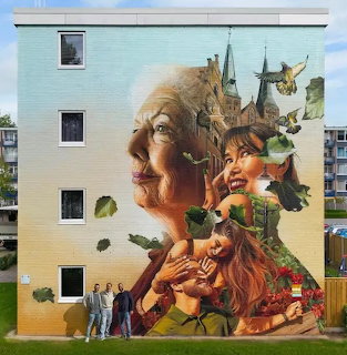 Street art mural on a building wall with layered faces, leaves, birds, and castle-like structures