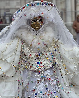 Person in ornate white Venice carnival costume with decorative mask, jeweled outfit, and elaborate headdress