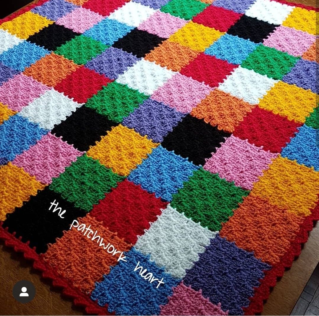 Colorful patchwork rug with multicolored squares in checkered pattern on wooden floor