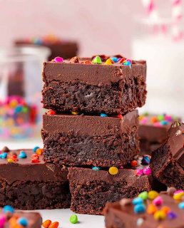 Stack of three chocolate brownies with frosting and rainbow sprinkles
