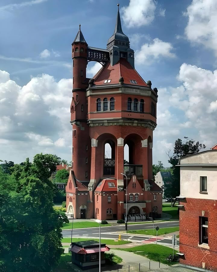 Historic red brick water tower with arched openings and clock tower in Poland