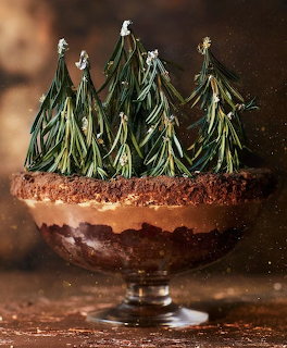 Chocolate layered dessert with white chocolate Christmas tree decorations in glass serving dish