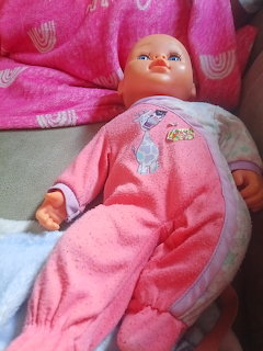 Baby doll in pink outfit resting on pink fabric