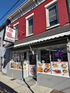 Red brick two-story building with corner grocery store, white awning, and large storefront windows