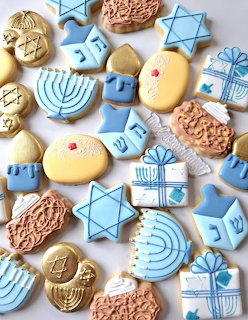 Assorted Hanukkah cookies with blue and gold icing showing Jewish symbols like menorahs, dreidels, and Stars of David