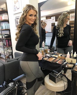 Woman in black top and light pants standing in modern salon with mirrors