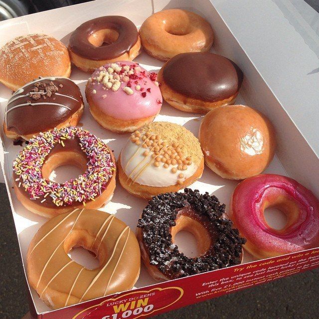 Dozen assorted donuts with chocolate, pink, and caramel glazes and colorful sprinkles in a white box
